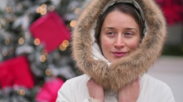 Happy woman wearing white winter coat at the christmas market with decorations smiling
