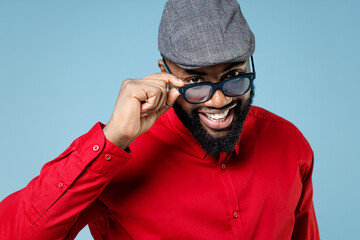 Close up of smiling funny young bearded african american man 20s wearing casual red shirt cap...