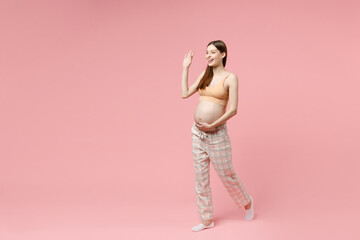 Fototapeta na wymiar Full body length young pregnant woman in basic top stroking keeping hands on big belly stomach tummy with baby isolated on pastel pink background studio Maternity family pregnancy expectation concept