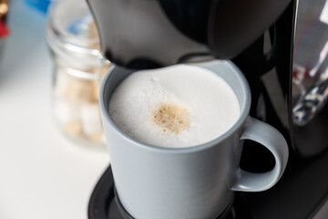 The coffee machine pours cappuccino into the cup. Coffee-make, coffee from the machine at home. Close-up of espresso making from a coffee machine
