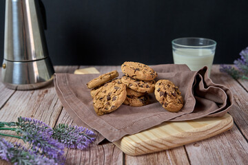 Chocolate cookies with a glass of milk and a jug of coffee on a wooden table