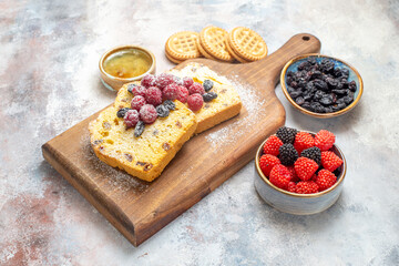 bottom view raisin cake slices with raspberries on cutting board bowls with raisins raspberry candies and biscuits on marble ground