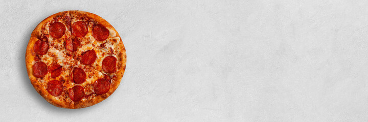Tasty pizza banner with salame on bright concrete surface with place for your text. Top view of pepperoni sliced pizza. 