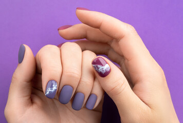 Beautiful purple burgundy matte manicure on creative background