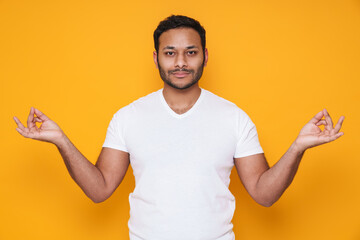 Asian young unshaven man meditating and holding fingers together