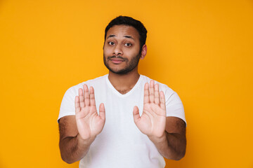 Asian brunette unshaven concentrated man doing stop gesture with hands