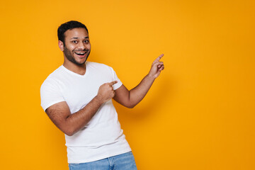 Asian young unshaven man smiling and pointing his fingers aside