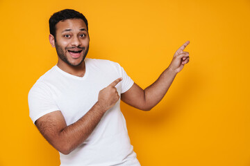 Asian young unshaven man smiling and pointing his fingers aside