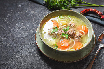 Meatball soup and ingredients on stone table.