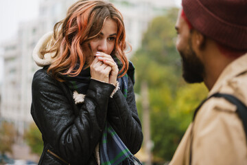 Beautiful girl warming her hands while talking with her boyfriend
