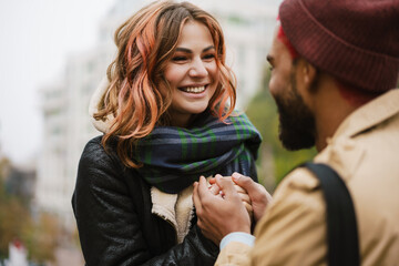 Multinational beautiful joyful couple smiling and warming their hands