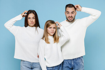 Preoccupied puzzled young parents mom dad with child kid daughter teen girl in white sweaters put...