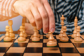 The man in the plaid shirt moves a chess piece, the concept of strategy and leadership