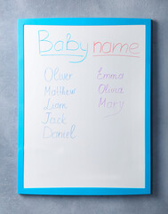 White board with baby names on grey wall
