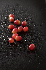 Top view closeup of red grapes isolated on a black background with water drops