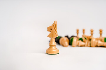 Chess piece knight on a white background, behind the team in the form of chess pieces