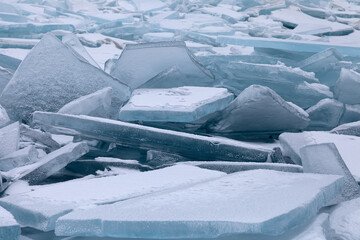Pile of broken ice floes covered with snow, winter landscape or background in white and blue tones, close-up view