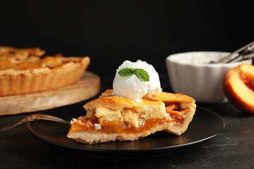 Slice of delicious peach pie with ice cream on black table