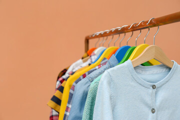 Rack with stylish children clothes on beige background, closeup. Space for text
