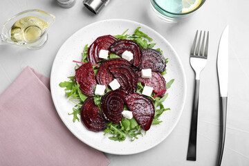 Roasted beetroot slices with feta cheese and arugula served on light grey table, flat lay