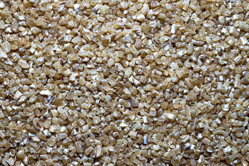 Raw fine Crushed Wheat groats  texture background. Close up Macro shot