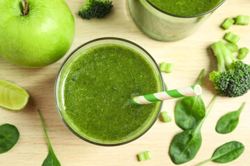 Delicious green juice and fresh ingredients on wooden table, flat lay