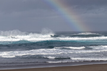 Wave and rainbow, winter time at the Azores, beach in Ribeira Grande.	
