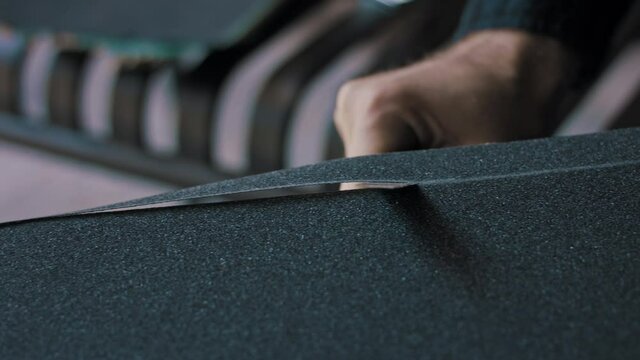 Man cutting away the extra grip tape on his skateboard 