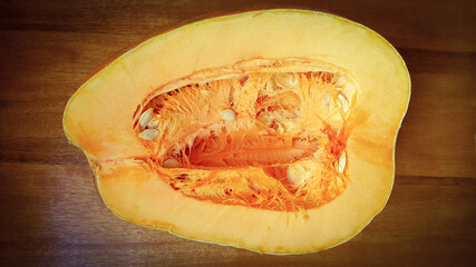 A large pumpkin carved in the middle on a wooden table. On the subject of fruits and vegetables.