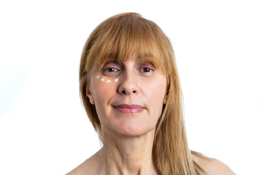 Older Woman With Blonde Hair Smiling With Anti-wrinkle Cream On Her Face