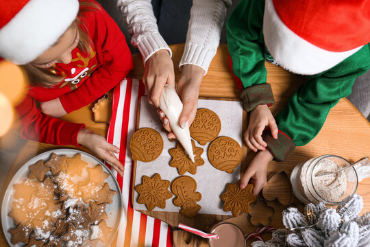 Mother And Her Little Children Decorating Tasty Christmas Cookies At Wooden Table, Top View