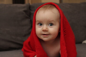 Close-up portrait of cute baby girl in a red blanket