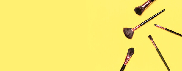 Professional makeup brushes on Illuminating yellow background flat lay top view. Pantone color of year 2021. Beauty product, makeup, women's accessory, fashion. Different brushes. Cosmetic makeup Set