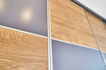 Wooden wardrobe door panels made of light brown natural oak timber with elegant texture patterns and blank grey parts