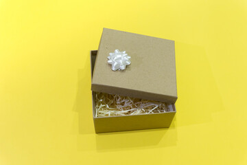 Gift box with white bow decoration on a yellow background. Lighting. Color of the year 2021. Milimalism. Concept for sales, shopping, valentine's day, christmas holidays and birthday