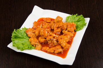 fried chicken with garnish and sauce and herbs in a white plate on a wooden background