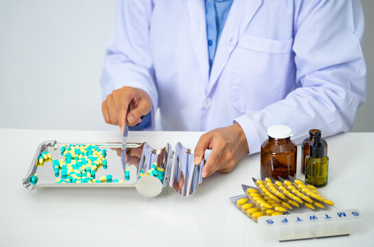 Close up shot of pharmacist counts out medicines for a customer.Doctor counting pills on pharmaceutical tray - Powered by Adobe