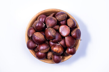 Chestnuts in a wooden bowl on white background. Castanea sativa, sweet ripe Chestnuts, top view