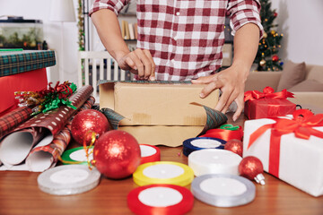 Cropped image of man wrapping gifts for friends and relatives and decorating with ribbons and baubles