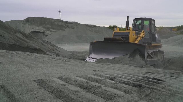 Caterpillars bulldozer climbs uphill with rubble, rowing rubble uphill
