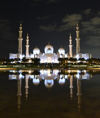 Fototapeta na wymiar Spiegelung der nächtlich beleuchteten Scheich-Zayid-Moschee auf blanker Wasseroberfläche