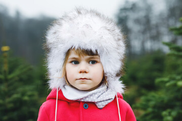 Winter portrait of adorable cute toddler girl of three years. Beautiful baby with cute fur hat...