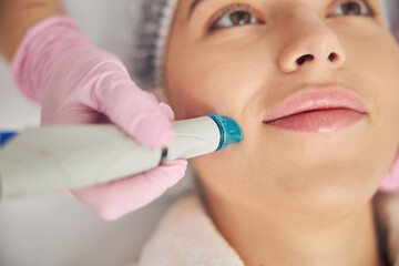 Professional female cosmetologist performing a hydrodermabrasion treatment