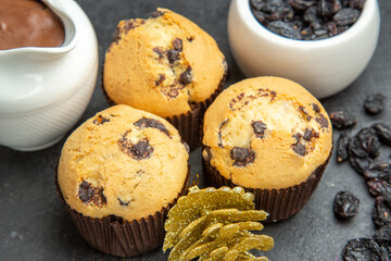 Close up view of delicious freshly baked small cupcakes chocolate black raisins and accessories on dark background