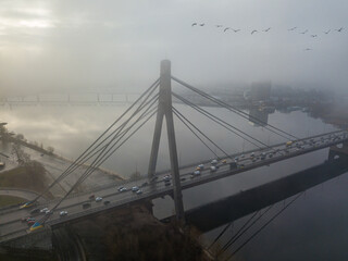 Aerial drone view. North bridge in Kiev, shrouded in morning fog. Seagulls fly over the bridge.