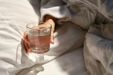 A glass of water next to a girl sleeping in bed. Happy morning. Woman in pyjamas. Healthy...