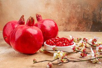 front view fresh red pomegranates peeled and with whole fruits on brown background color fruit photo