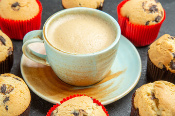 Close up view of delicious coffee around small cupcakes on dark background