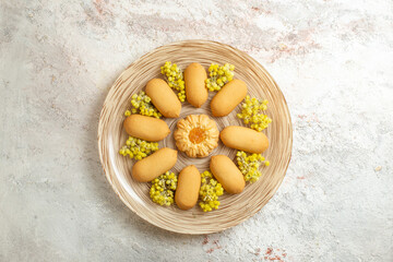 Fototapeta na wymiar pile of cookies on a plate with bright yellow flowers on a marble background