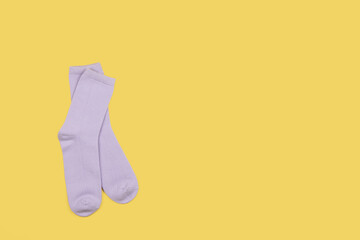 Lilac children's socks without pattern, isolated on yellow background with copy space, flatly, minimal style. Concept kid's clothing, housekeeping, sorting, decluttering, organizing